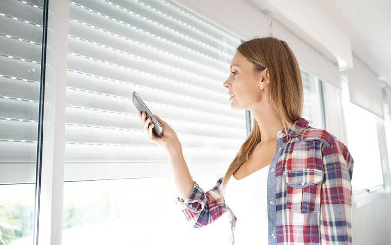 femme qui ouvre un volet roulant solaire